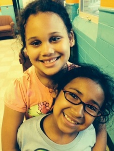 Two smiling girls hugging indoors
