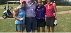 Four smiling golfers posing on green