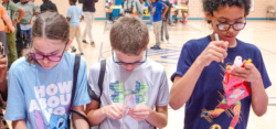 Three children making crafts in school gym